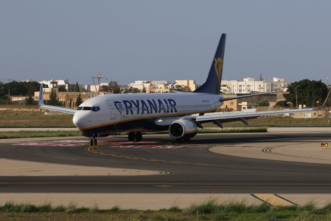 Ryanair airplane taxiing on runway in sunny weather at an airport in daylight.